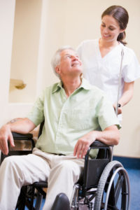 Nurse Pushing Man In Wheelchair - iStock